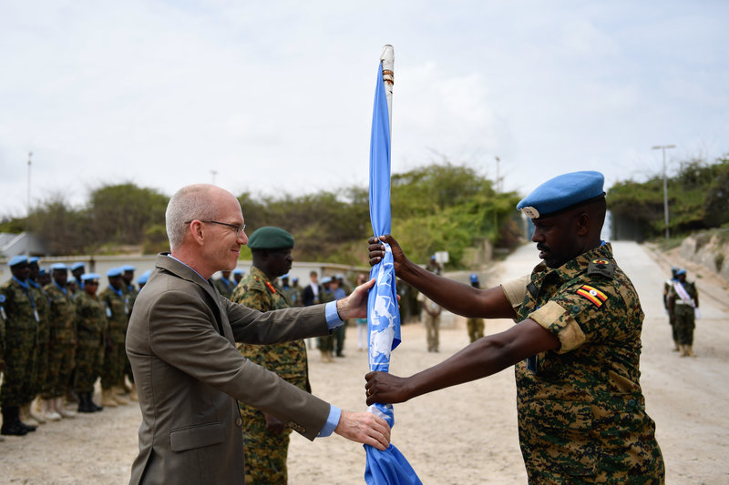 The outgoing commander of the United Nations Guard Unit, Lt. Col. Stuart Agaba (right), hands over a UN flag to the UN Secretary-General's Special Representative for Somalia, James Swan, during the command hand over/take over ceremony held in Mogadishu, S